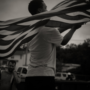 Protester waves an American flag at the Quick Trip on the corner of W. Florissant  